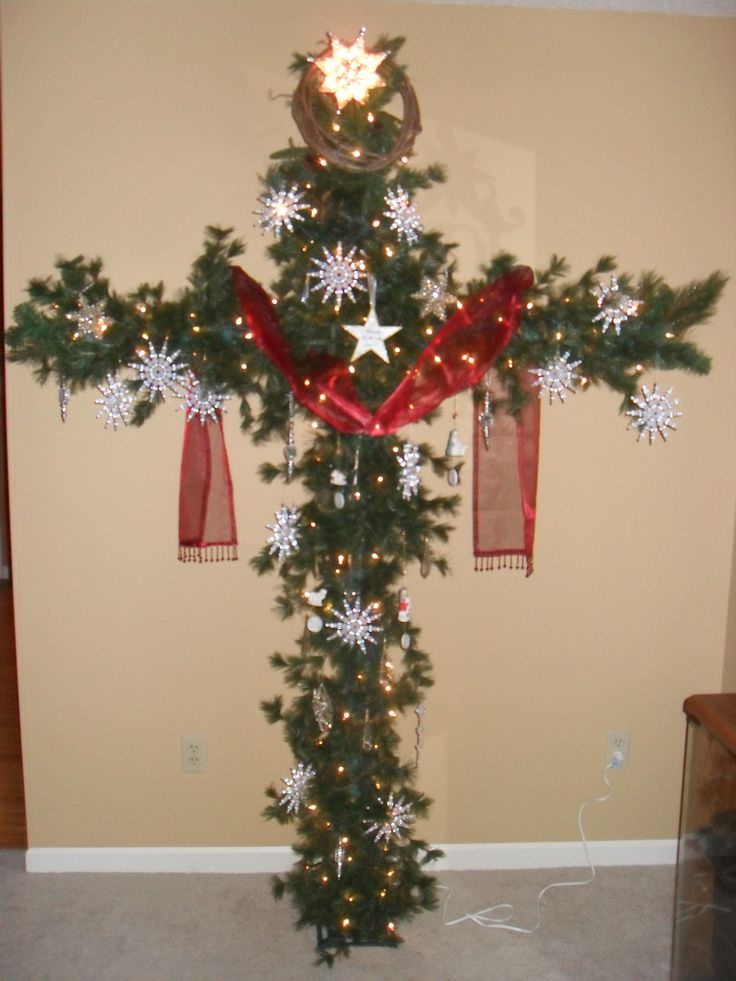 a christmas tree decorated with red ribbon and snowflakes is displayed in front of a wall