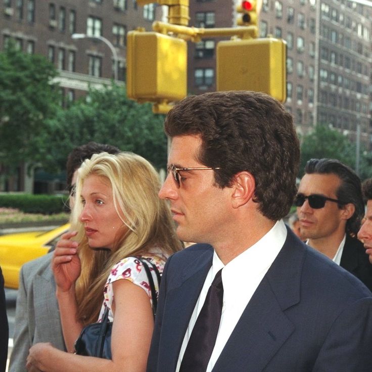 a group of people standing on the side of a road next to each other in suits and ties