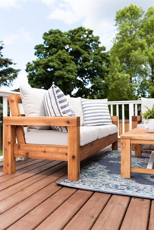 two wooden benches sitting on top of a wooden deck next to a table and chairs