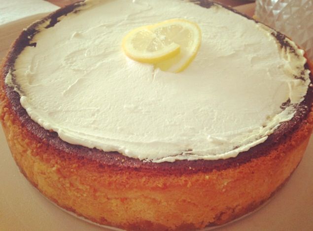 a cake with white frosting and a lemon slice on top is sitting on a table