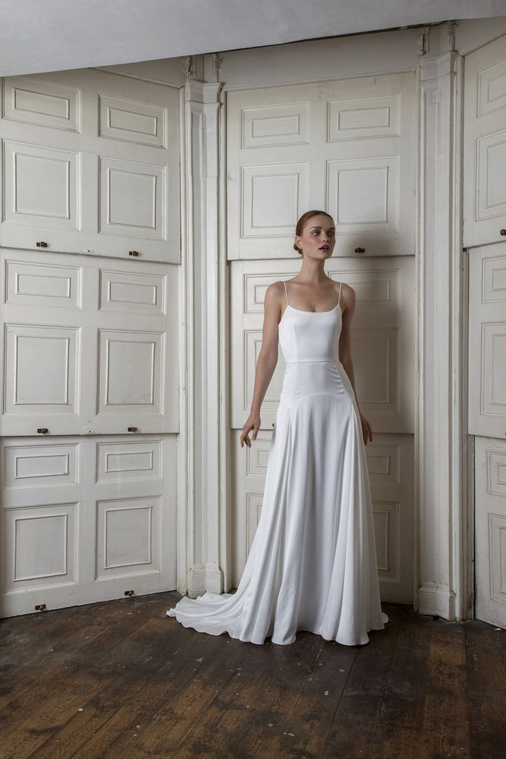 a woman in a white wedding dress standing on a wooden floor next to two doors