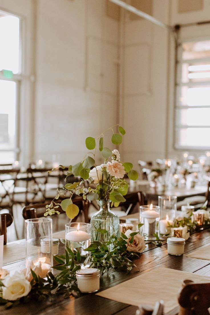 the table is set with candles, flowers and greenery for an elegant wedding reception