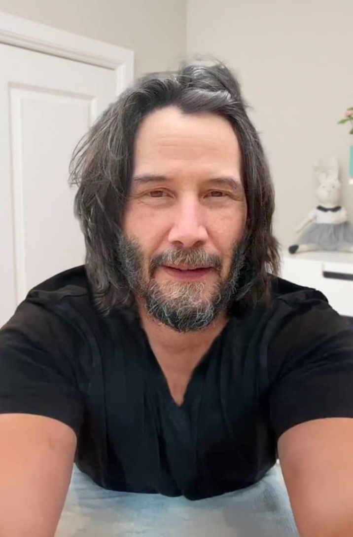 a man with long hair and beard sitting at a table in front of a white door