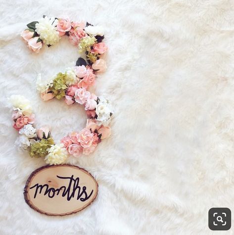 a wooden sign that says mom's with flowers around it on a white fur surface