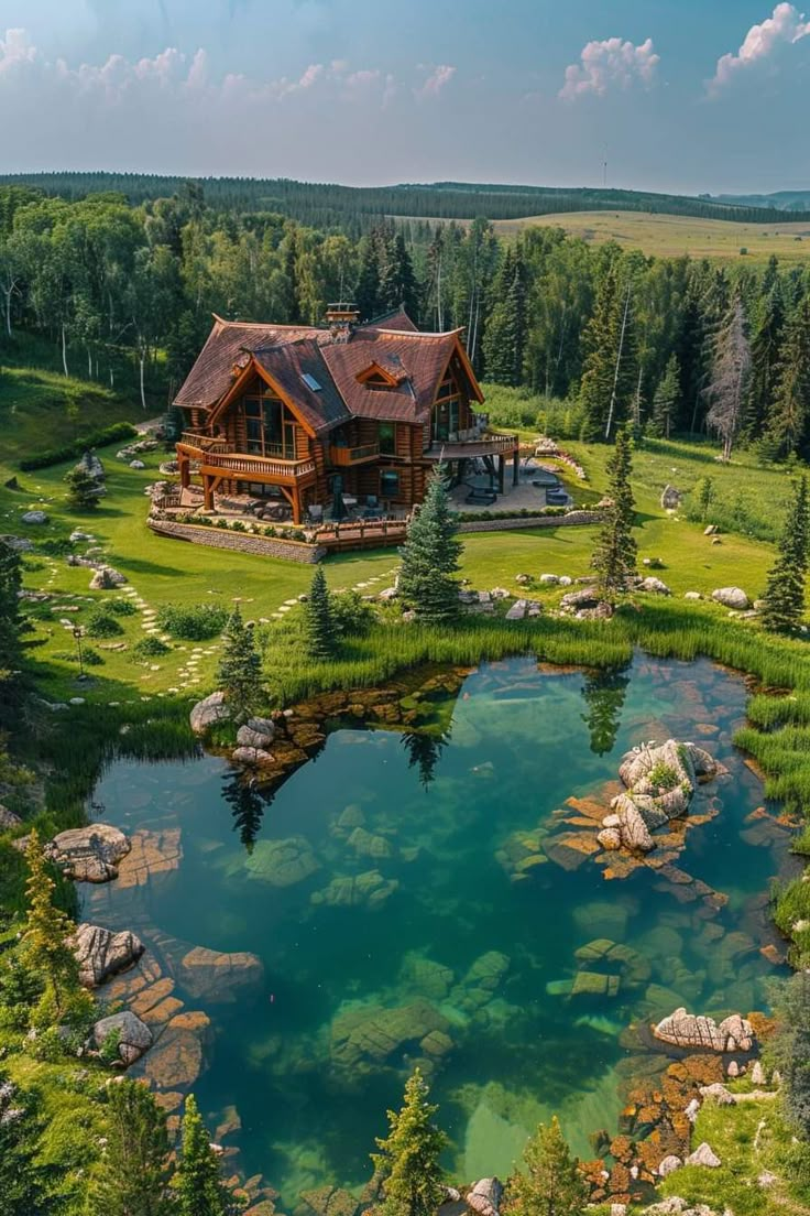 an aerial view of a house in the middle of a lake surrounded by pine trees