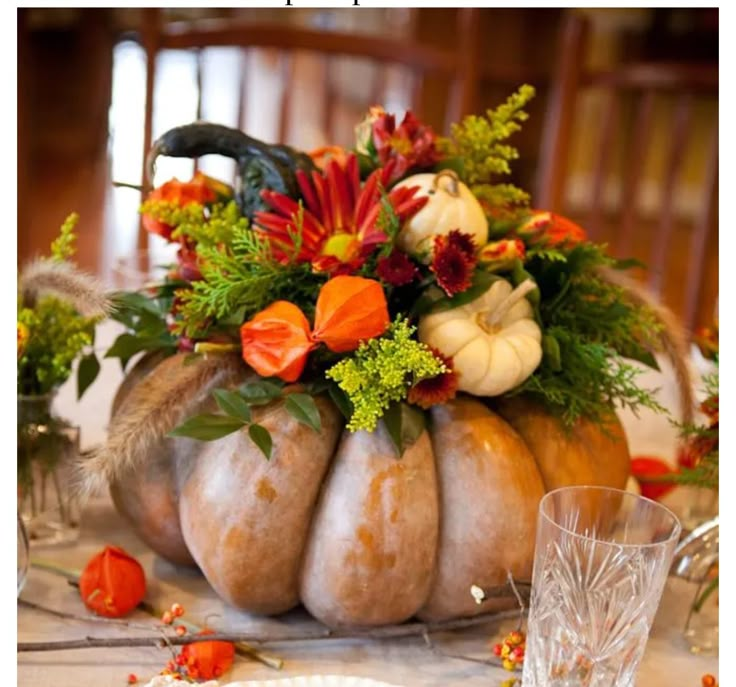 an arrangement of pumpkins and flowers on a table