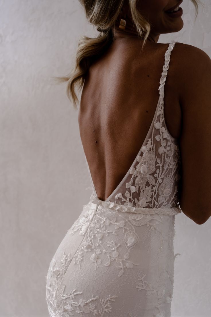 the back of a woman wearing a wedding dress with an open back and lace detailing