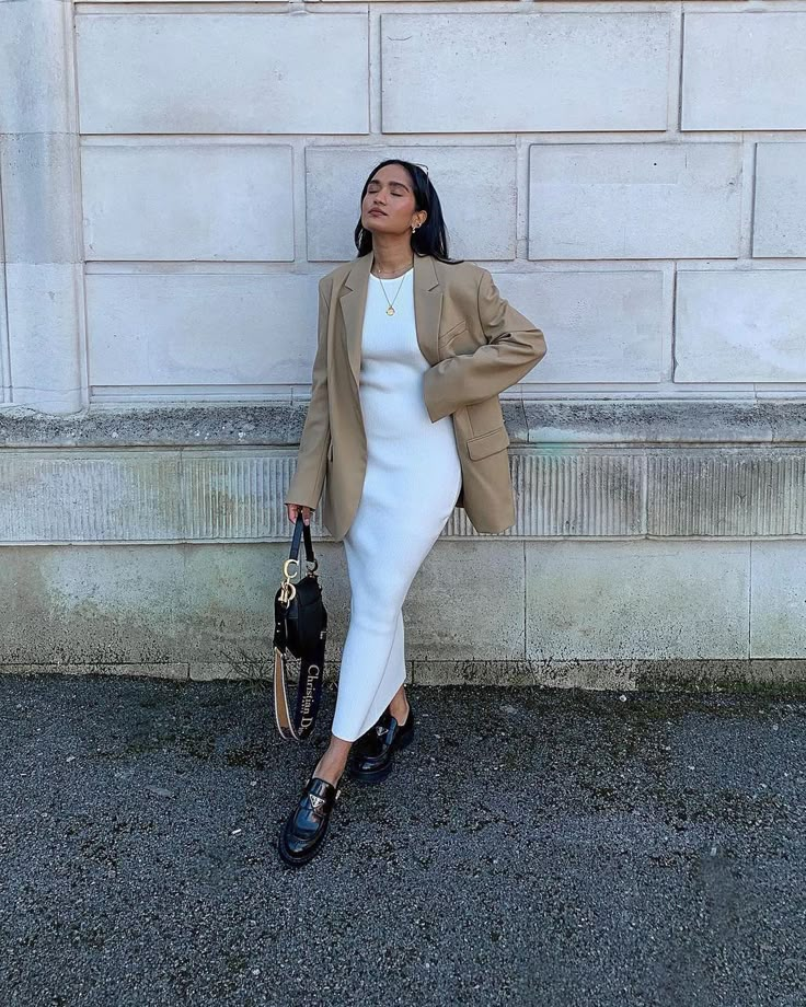 P R E T T Y L A V I S H on Instagram: “We love how @divrav has styled her cream Billie dress with a neutral oversized blazer, simple gold jewellery and black leather accessories…” White Dress And Blazer Outfit, Knit Dress And Blazer Outfit, Oversized Blazer With Dress Outfit, Midi Dress Blazer Outfit, Knitted Midi Dress Outfits, Cream Midi Dress Outfit, Blazer With Long Dress, Cream Knit Dress Outfit, Rib Dress Outfit