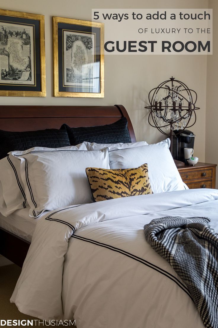 a bed with white sheets and pillows in front of two framed pictures on the wall