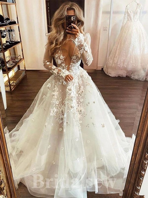 a woman taking a selfie in a wedding dress with flowers on the skirt and long sleeves