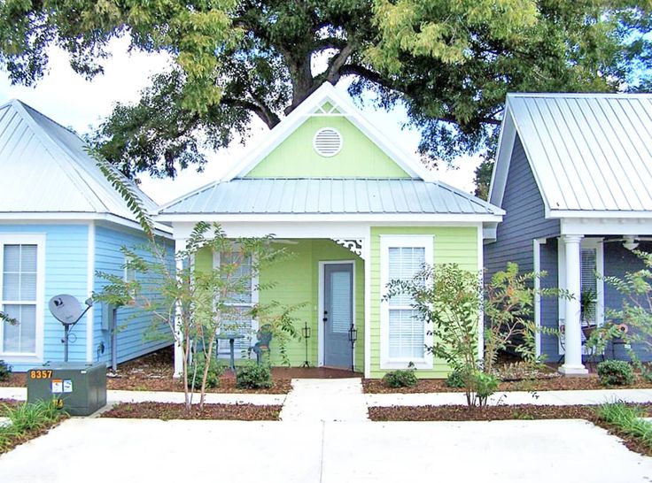 three small houses are painted blue, green and white with trees in the front yard