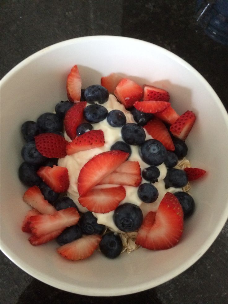 a bowl filled with strawberries and blueberries on top of a black countertop