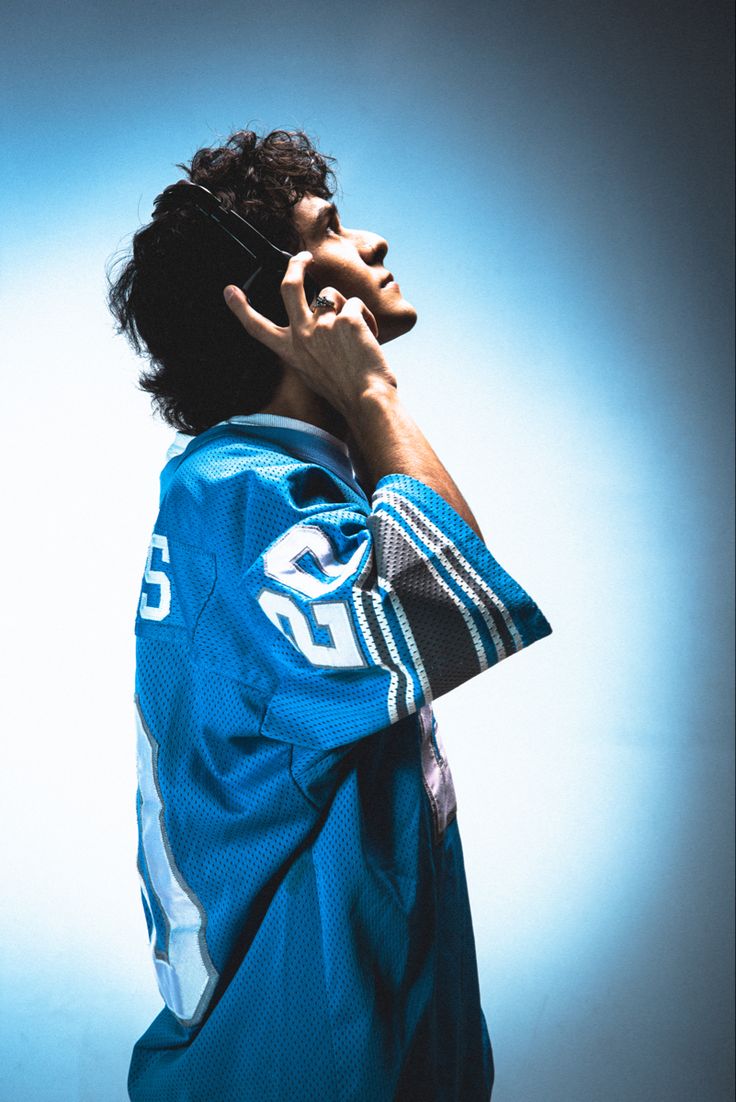 a man talking on a cell phone while wearing a jersey