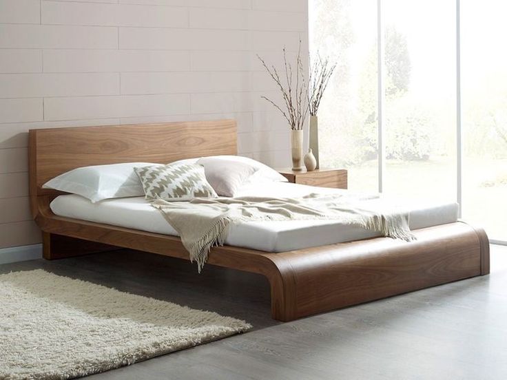 a bed with white sheets and pillows on top of it next to a rug in front of a window