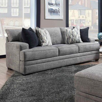 a living room scene with focus on the couch and pillows in the foreground, along with a large window