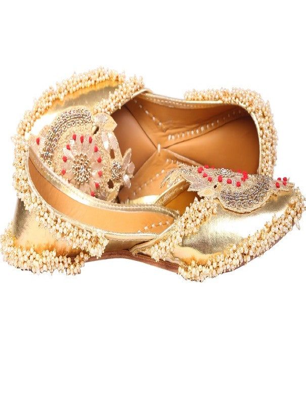 Bringing class to your wardrobe with our beautifully handcrafted 'golden Crown' juttis. Glossy silver based adorned with palmette like motif that is embroidered with gotapatti and silver dabka work. We added bunches of ivory beads to give it a fuller look. Asymmetrical neckline adds an extra glamour to the whole jutti. You can pair these up with an embroidered lehenga or saaree in contrasting color for a party or festive look! Color: Gold Fabric: Faux Leather Upper- Silver faux Leather - leather Gold Embellished Traditional Wear For Reception, Silver Embellished Traditional Wear, Embellished Silver Traditional Wear, Festive Gold Embellished Traditional Wear, Gold Bollywood Traditional Wear With Handwork, Kundan Traditional Wear With Handwork For Festive, Embellished Kundan Traditional Wear For Festivals, Gold Kundan Traditional Party Wear, Gold Kundan Traditional Wear For Party