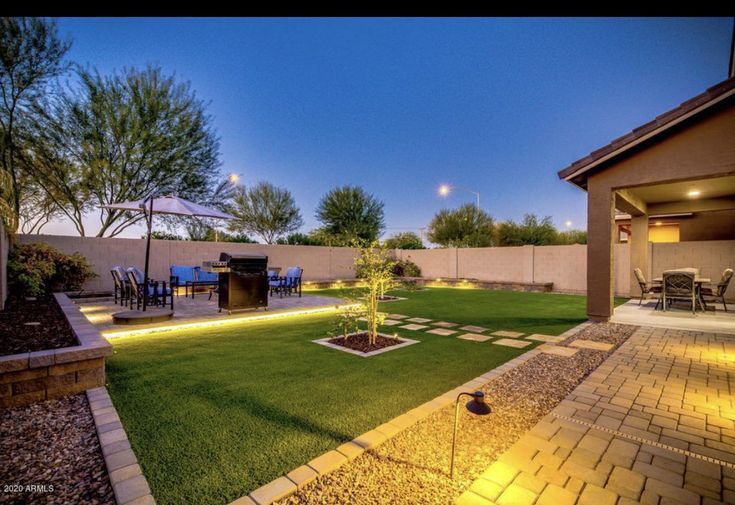 a backyard with grass and lights in the evening