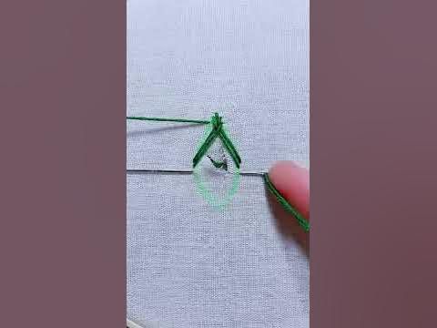 someone is stitching together green thread on a piece of fabric