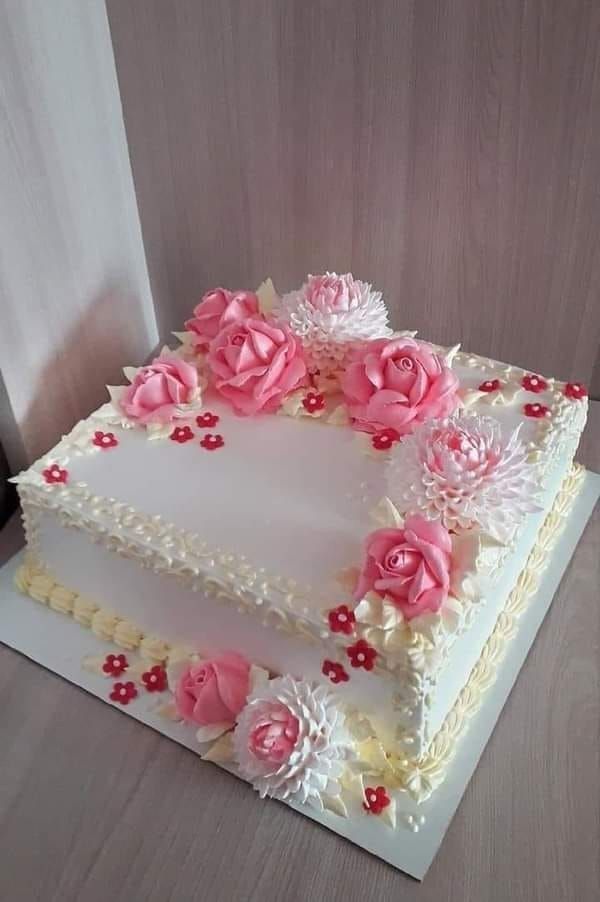 a square cake with white frosting and pink flowers