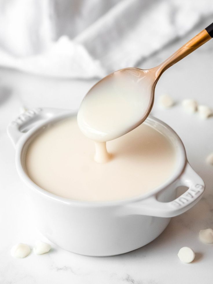 a spoon full of milk being poured into a bowl