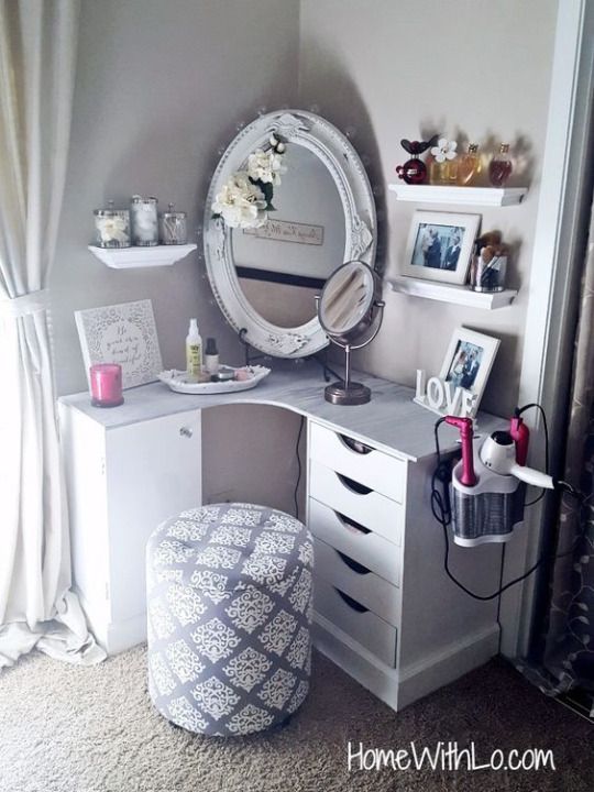 a vanity with a mirror, stool and pictures on the wall