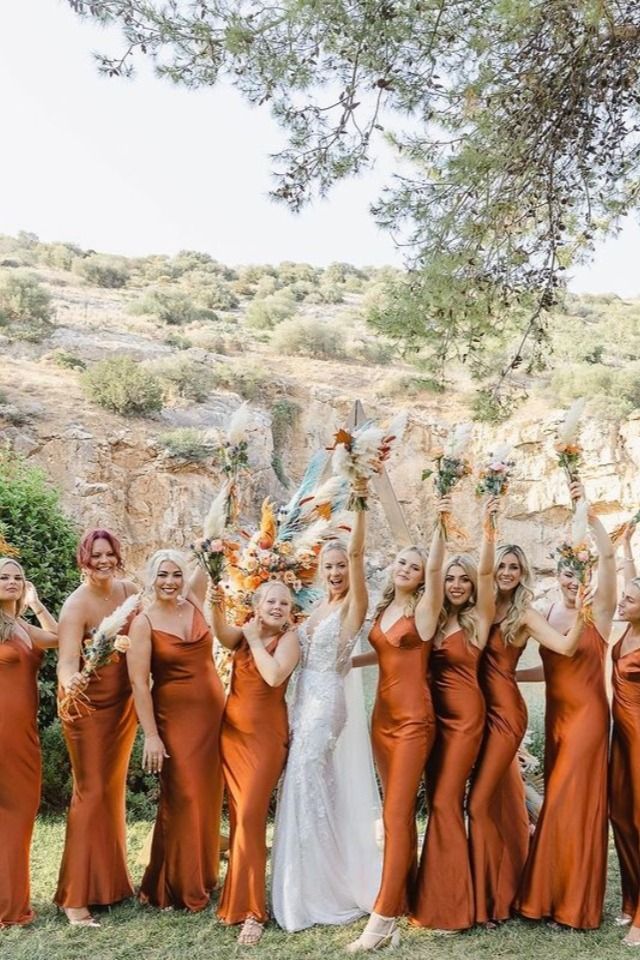 a group of women in dresses standing next to each other holding up their hands together