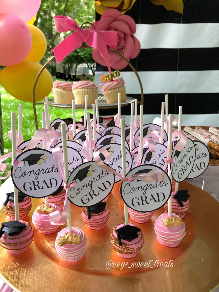 desserts and cupcakes are displayed on a gold platter at a graduation party