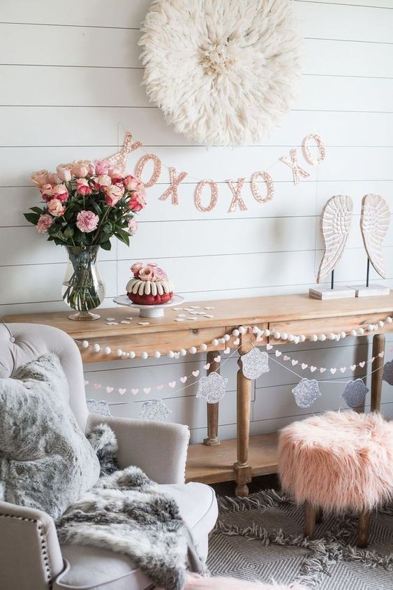 a living room with pink and white decor on the wall, two chairs and a table