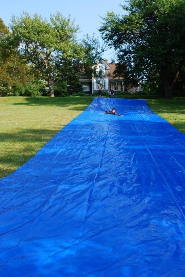 a large blue tarp covering a lawn in the middle of a yard with trees