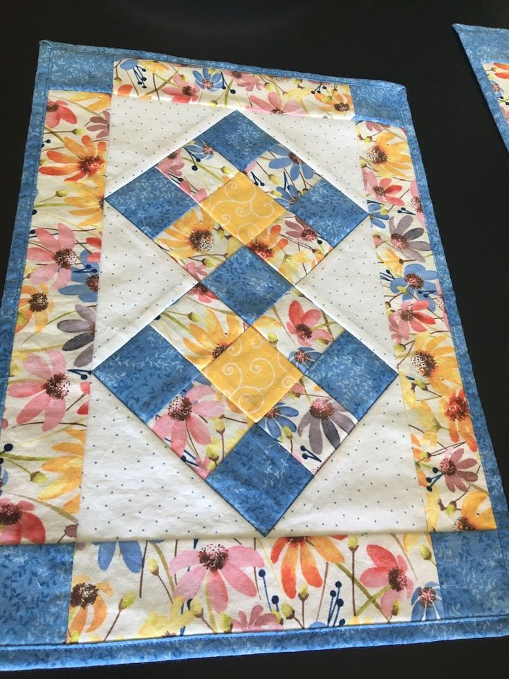 two quilts are laying next to each other on top of a blue table cloth