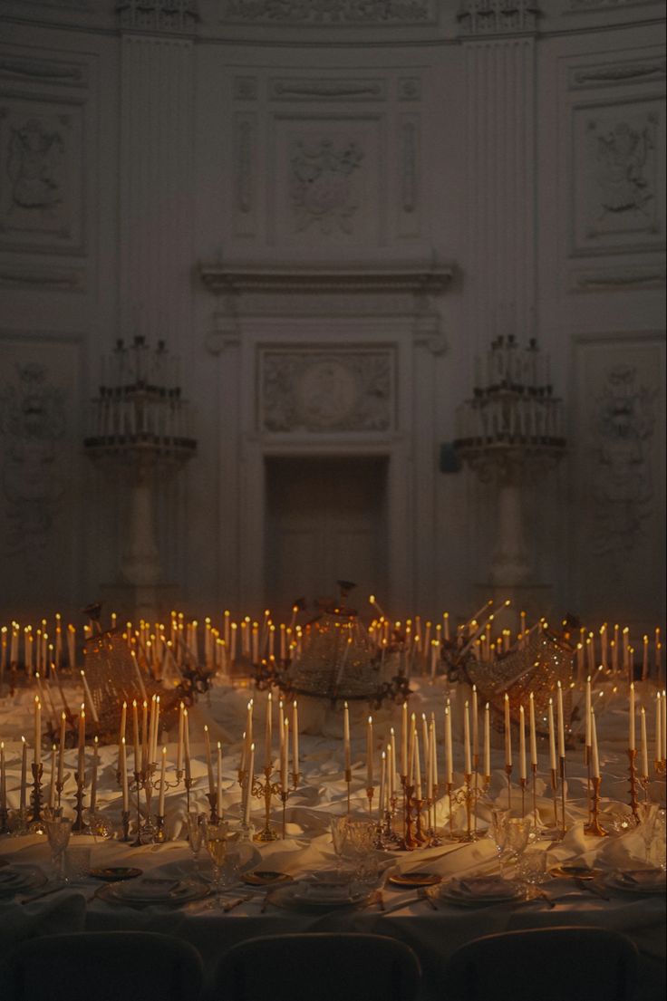 many candles are lit in the middle of a room with white walls and ornate carvings