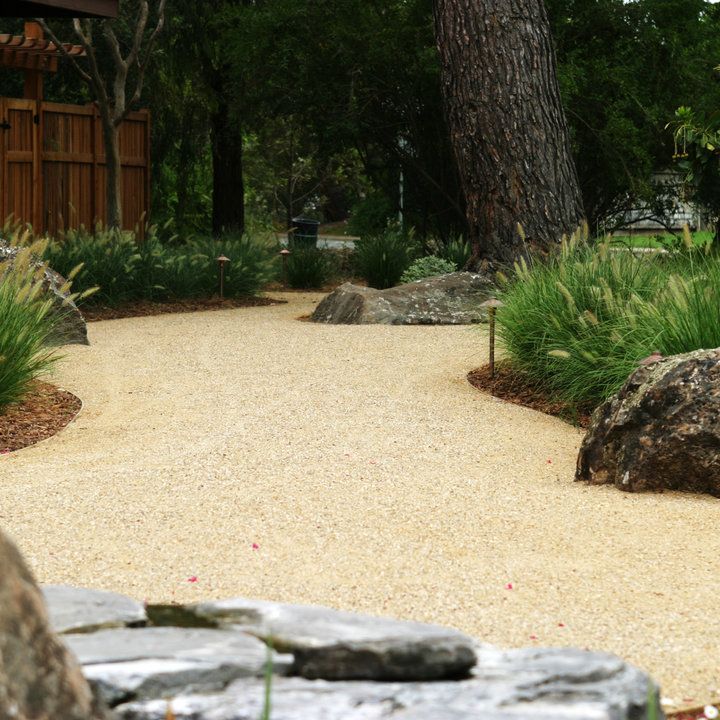 a gravel path surrounded by trees and rocks