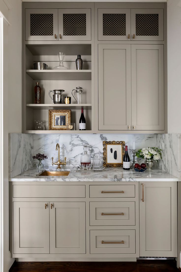 a kitchen with white cabinets and marble counter tops, gold accents on the sink area