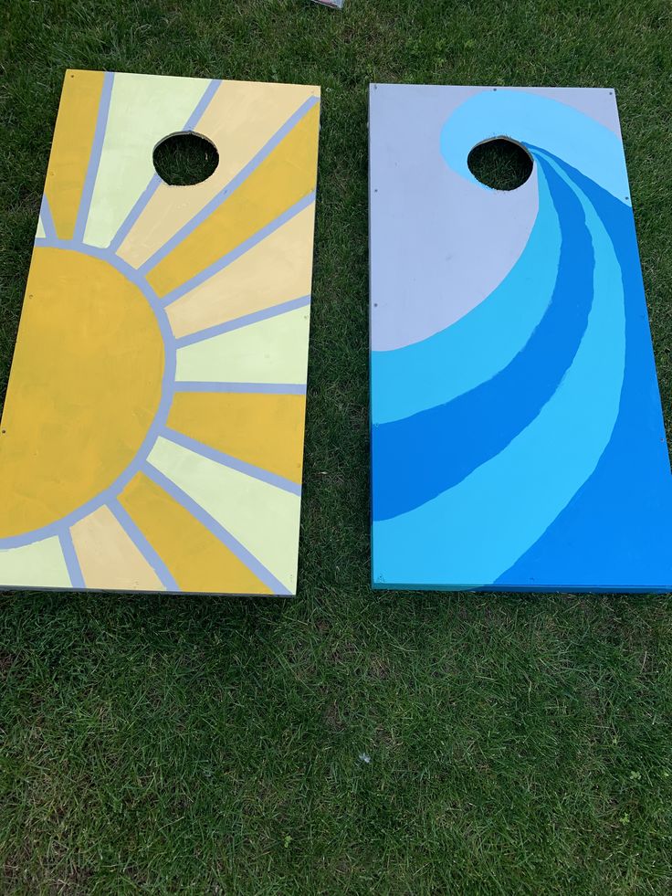 two painted cornhole boards sitting on top of a grass covered field next to each other