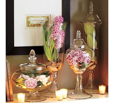 flowers and candles sit on a table in front of a mirror with an ornate frame