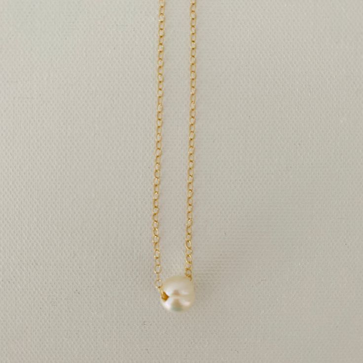 Just A Pearl! This simple yet elegant necklace is part of my Just A Pearl collection. One single pearl dangles from a delicate gold necklace. It measures 16 inches and length and can be adjusted to 15 inches for choker length. Minimalist White Chain Necklace With Pearl Pendant, Classic Pearl White Chain Necklace With Pearl Pendant, Classic White Pearl Charm Necklaces, Minimalist Everyday Charm Necklace With Pearl Chain, Elegant Everyday Charm Necklace With Simple Design, Classic Gold Charm Necklace With Pearl Drop, Classic Pearl Pendant Chain Necklace, Dainty Charm Necklace With Pearl Chain And Round Pendant, Classic Gold Pearl Chain Charm Necklaces