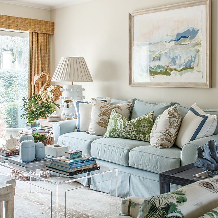 a living room filled with furniture and a painting on the wall above it's windows