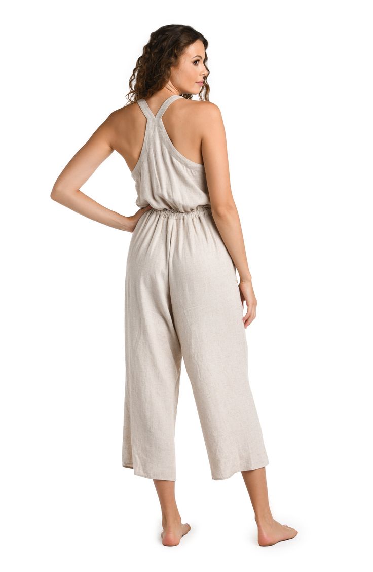 Effortlessly chic, this taupe-colored cover-up complements any beach ensemble, offering a versatile and neutral layer for your seaside adventures. This jumpsuit features a cropped, wide-leg design, with adjustable shoulder straps and a drawstring waist for a customizable fit. The back showcases a cross-strap detail, adding a touch of elegance to the relaxed fit, making it both functional and fashionable for summer days. [split] Details Jumpsuit cover up Cropped length Drawstring waistband Pocket Linen Jumpsuit For The Beach, Summer Beige Jumpsuits And Rompers With Elastic Waistband, Beach Jumpsuits And Rompers With Adjustable Straps, Chic Jumpsuits And Rompers With Adjustable Straps For Vacation, Beige Jumpsuits And Rompers With Elastic Waistband For Spring, Chic Beach Jumpsuits And Rompers With Adjustable Straps, Beige Sleeveless Jumpsuits And Rompers For Vacation, Versatile Spring Beach Jumpsuits And Rompers, Beige Linen Summer Jumpsuits And Rompers