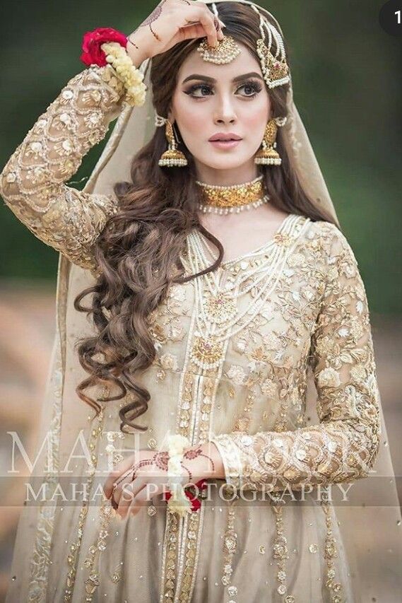 a woman wearing a bridal outfit and holding her hair in one hand, with the other