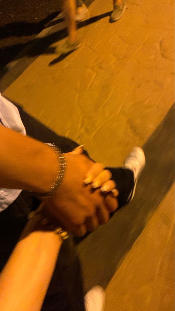 two people holding hands while sitting on the ground