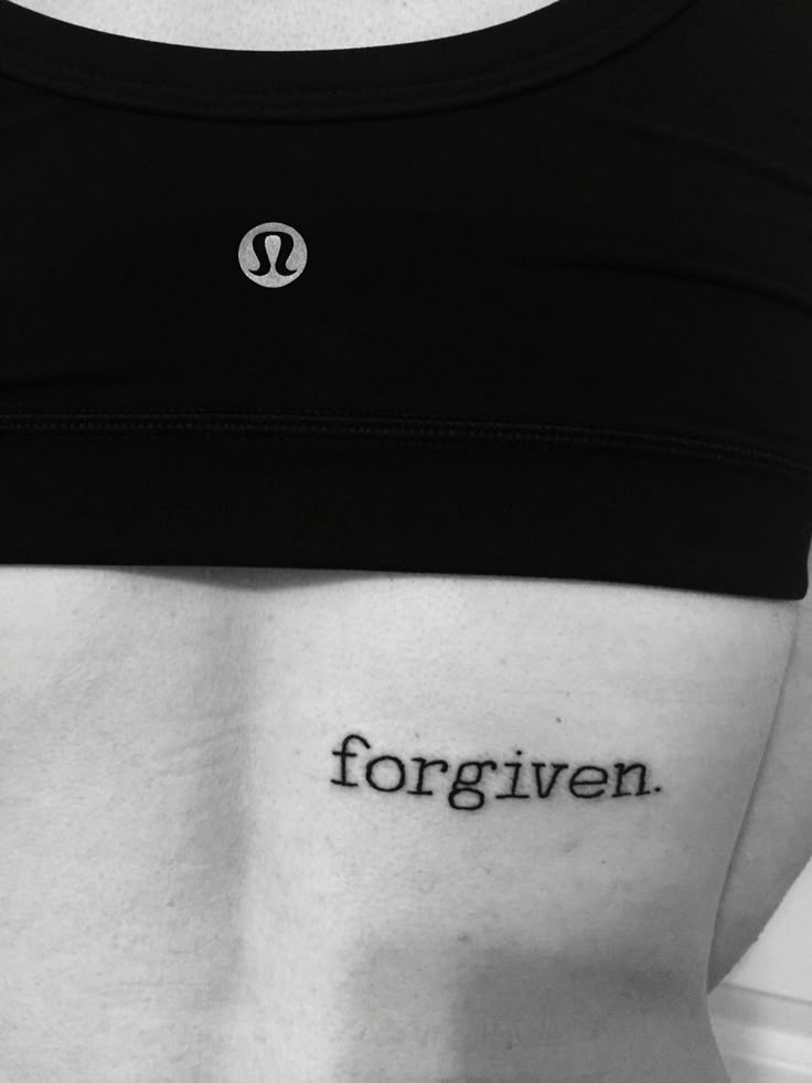 a woman's lower back with the word forgiven written in black ink