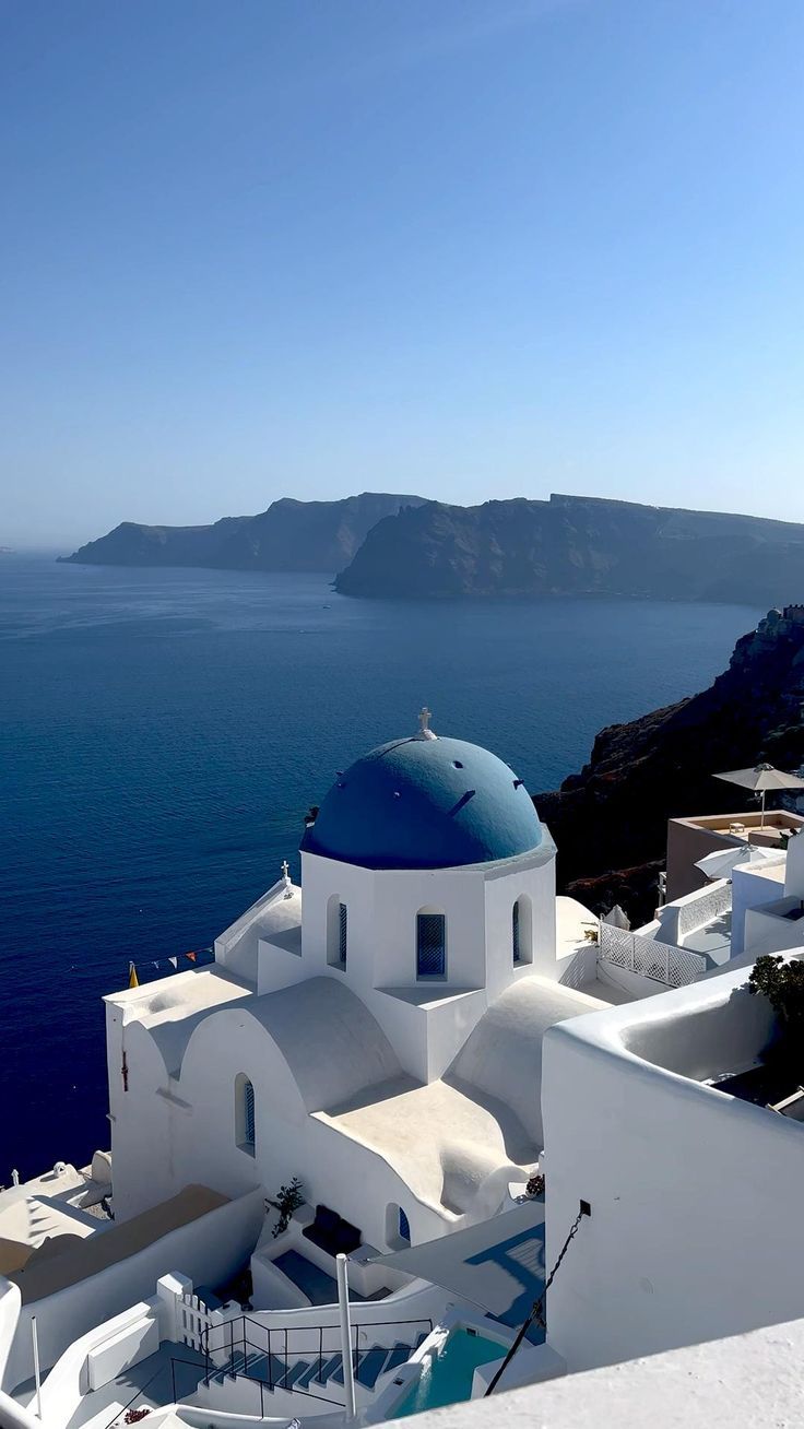 a woman sitting on top of a white building next to the ocean