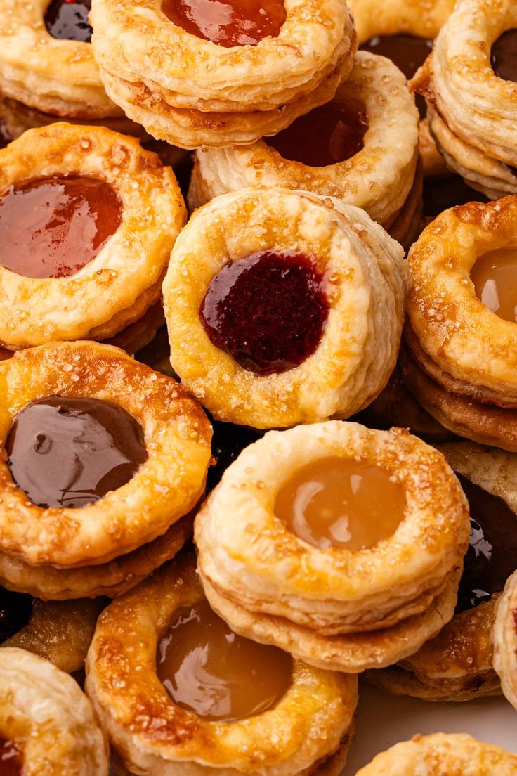 many small pastries with jam on them are piled up and ready to be eaten