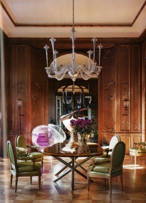 a dining room with wooden paneling and chandelier hanging from the ceiling, surrounded by green chairs