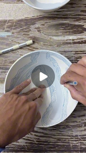 two people are working on a plate with the same design as one person's hands