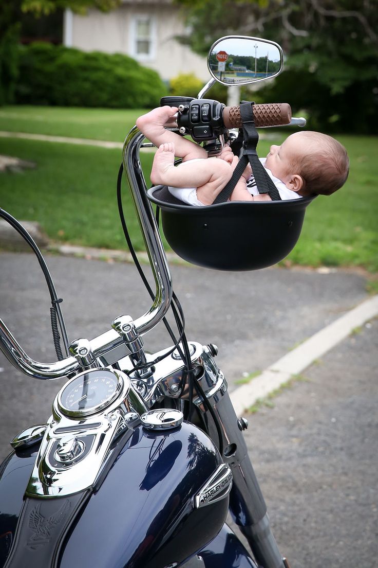 a baby laying in a basket on the handlebars of a motorcycle