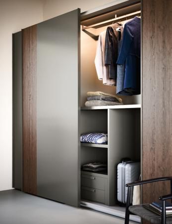 an open closet with clothes on hangers and suitcases in the room next to it