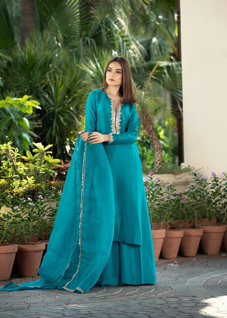 • Turquoise rawsilk handworked shirt with work on neckline (front and back) and sleeves with zardozi and dabka • Paired with matching rawsilk flared pants • Add on a pure katan organza dupatta with gota on four sides (Includes Shirt and pants) Pakistani Engagement Dresses Simple Salwar Kameez, Plan Suit Designs, Blue Pakistani Dress, Turquoise Color Combinations, Simple Suits, Engagement Mehndi, Desi Wedding Dresses, Lehenga Designs Simple, Embroidered Jewelry