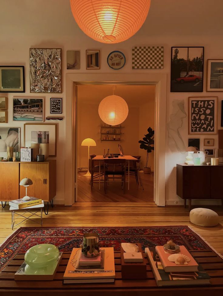 a living room filled with furniture and pictures on the wall next to a table in front of a doorway