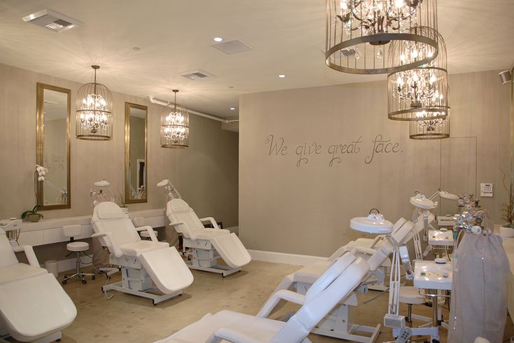 the interior of a nail salon with chandeliers hanging from the ceiling and white chairs